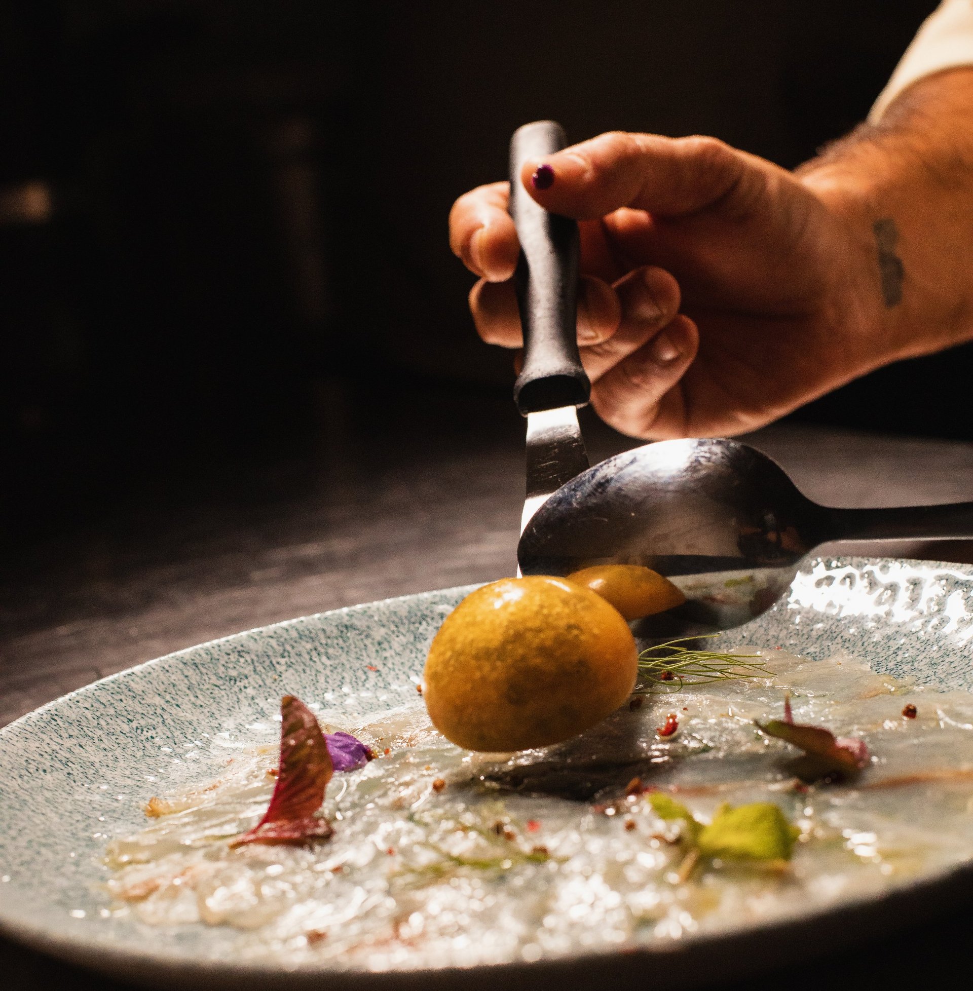 Close-up of chef placing food on a plate in a restaurant kitchen