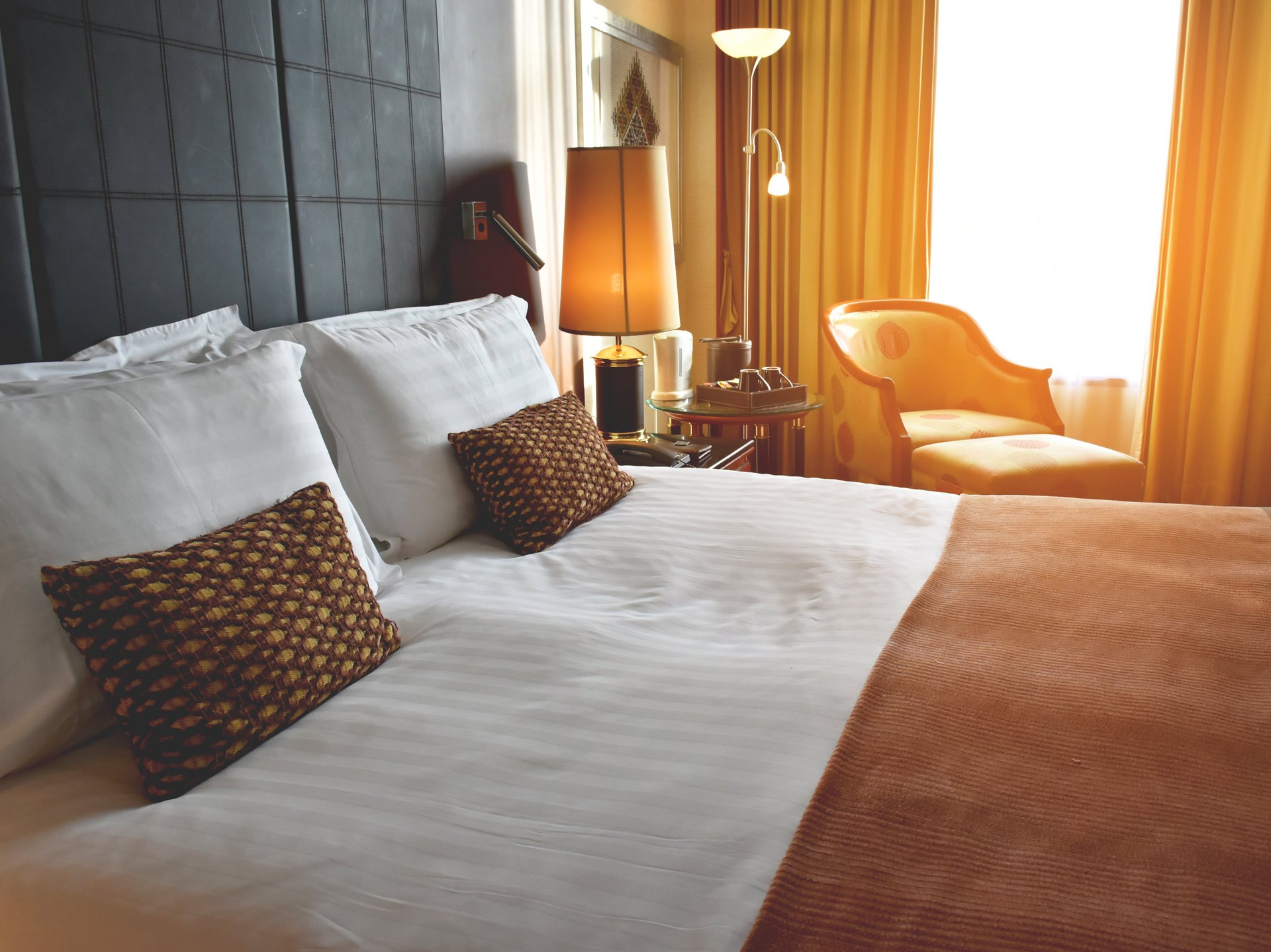 Hotel bedroom with sunshine coming through open curtains