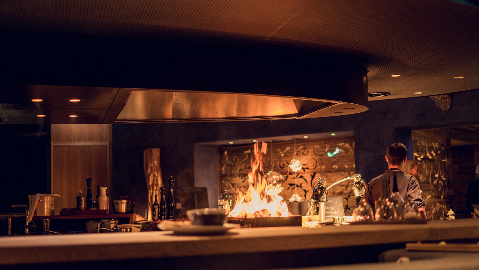 Restaurant interior showing open kitchen area with a flaming grill