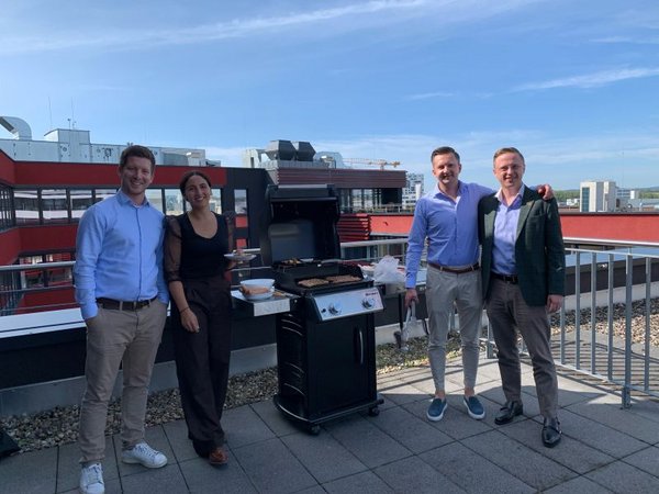 FutureLog team members standing together preparing a BBQ lunch on an outdoor terrace in Böblingen