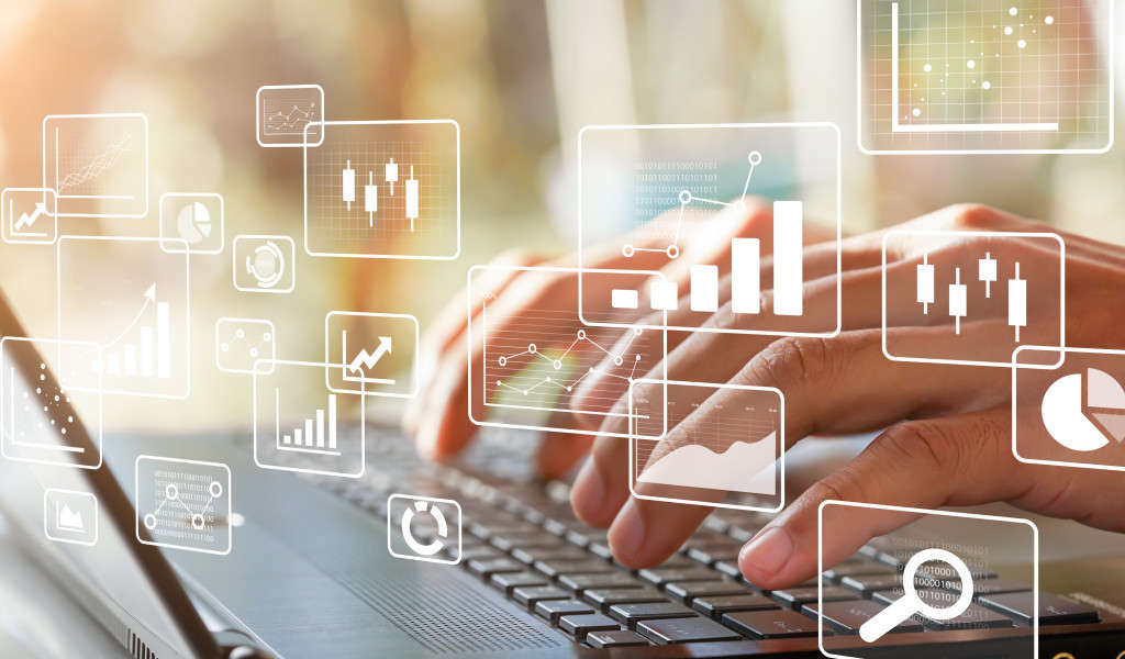 Close-up of fingers typing on keyboard with transparent visuals of graphs and charts in the foreground