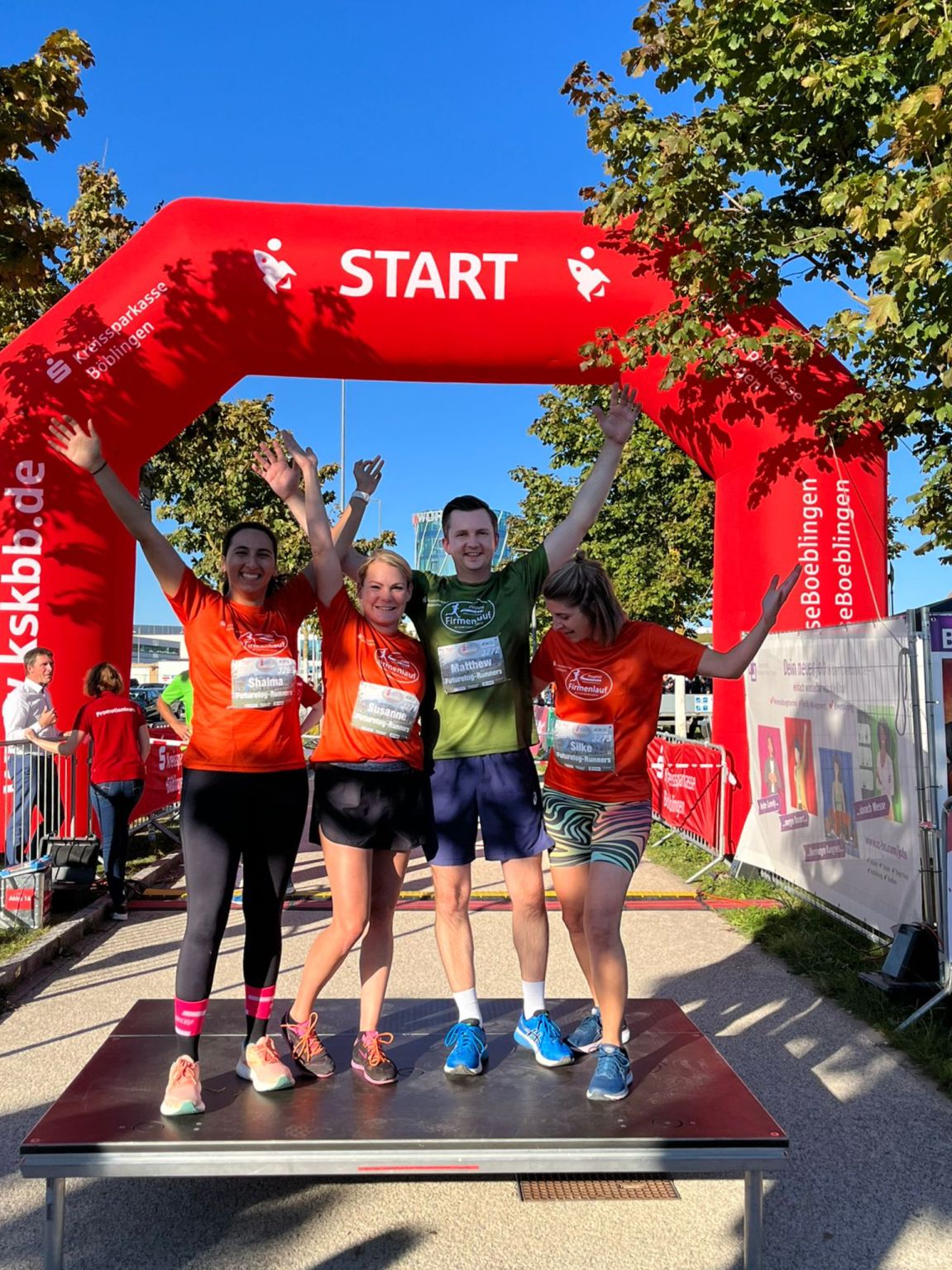 FutureLog team members in Böblingen cheering and celebrating the completion of their charity run, with the finish line in the background